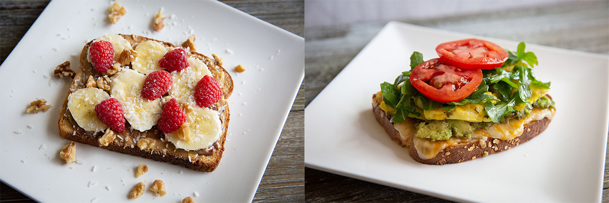 Split image of two differnet menu items. the first is a toast with peanut butter, bananas, rasberries, coconut and walnuts piled on top. The second is a piece of toast with chedder cheese, mashed avocado, a scambled egg, two slices of tomato and topped with augula. Both on white plate on a whitewashed wood table. 